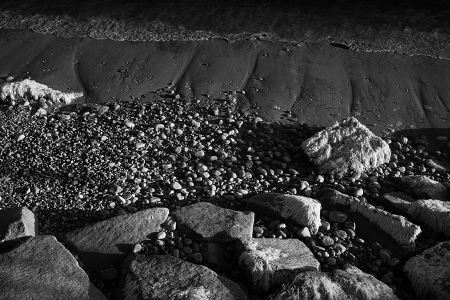 Infrared Photo of Rocks, Seaweed, Pepples, and Beach at Low Tide.